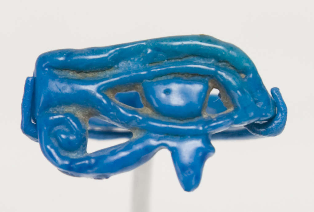 A blue-colored ring carved in the shape of an oval eye with a design in the shape of a spiral below the eye.  