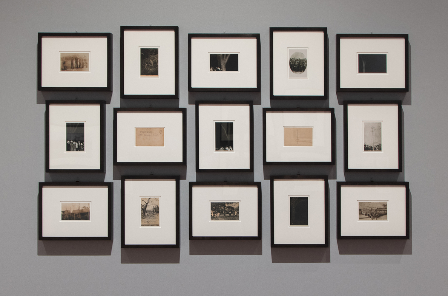 a grid of black and white post  cards on a gallery wall