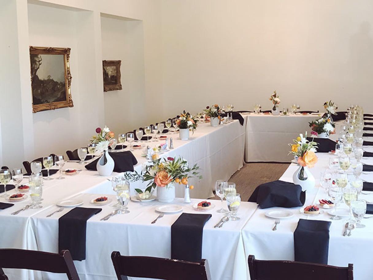Boardroom meeting space set for dinner flowers full place settings white and black linnens