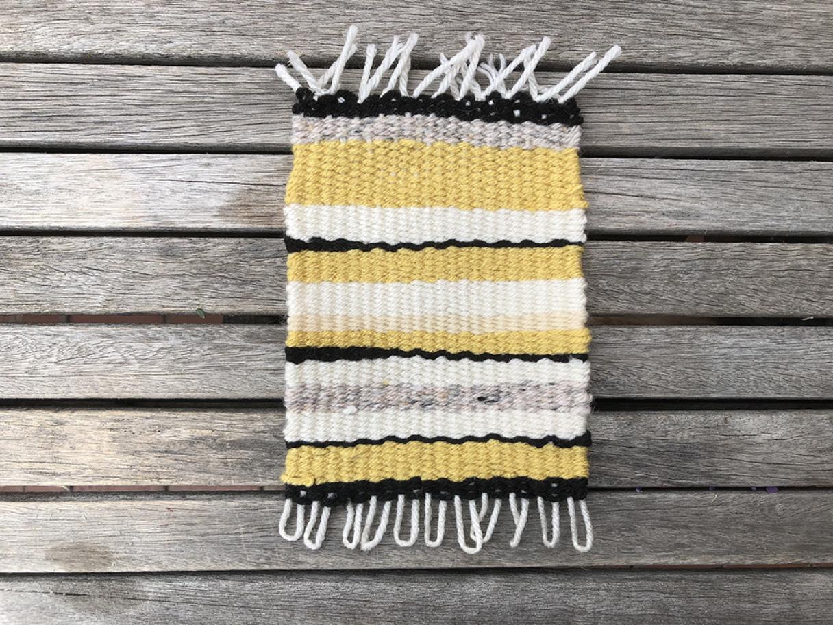 Handmade woven rug made with yellow, gray, white, and black yarn