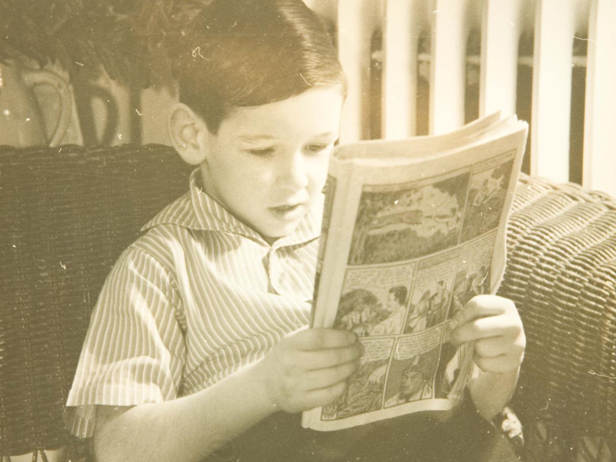 A young boy reads a comic book.