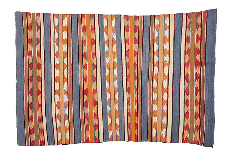 Wide Ruins Area Rug A woven rug with gray, orange, red, and white stripes. Some stripes have orange or red zigzag triangle shapes repeating throughout the stripe.