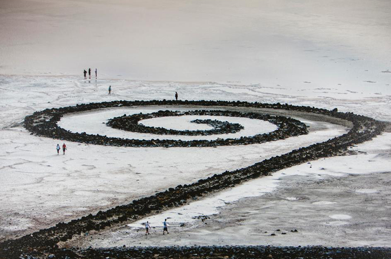 the spiral jetty made of black basalt rocks coils out against white, salty sand. 