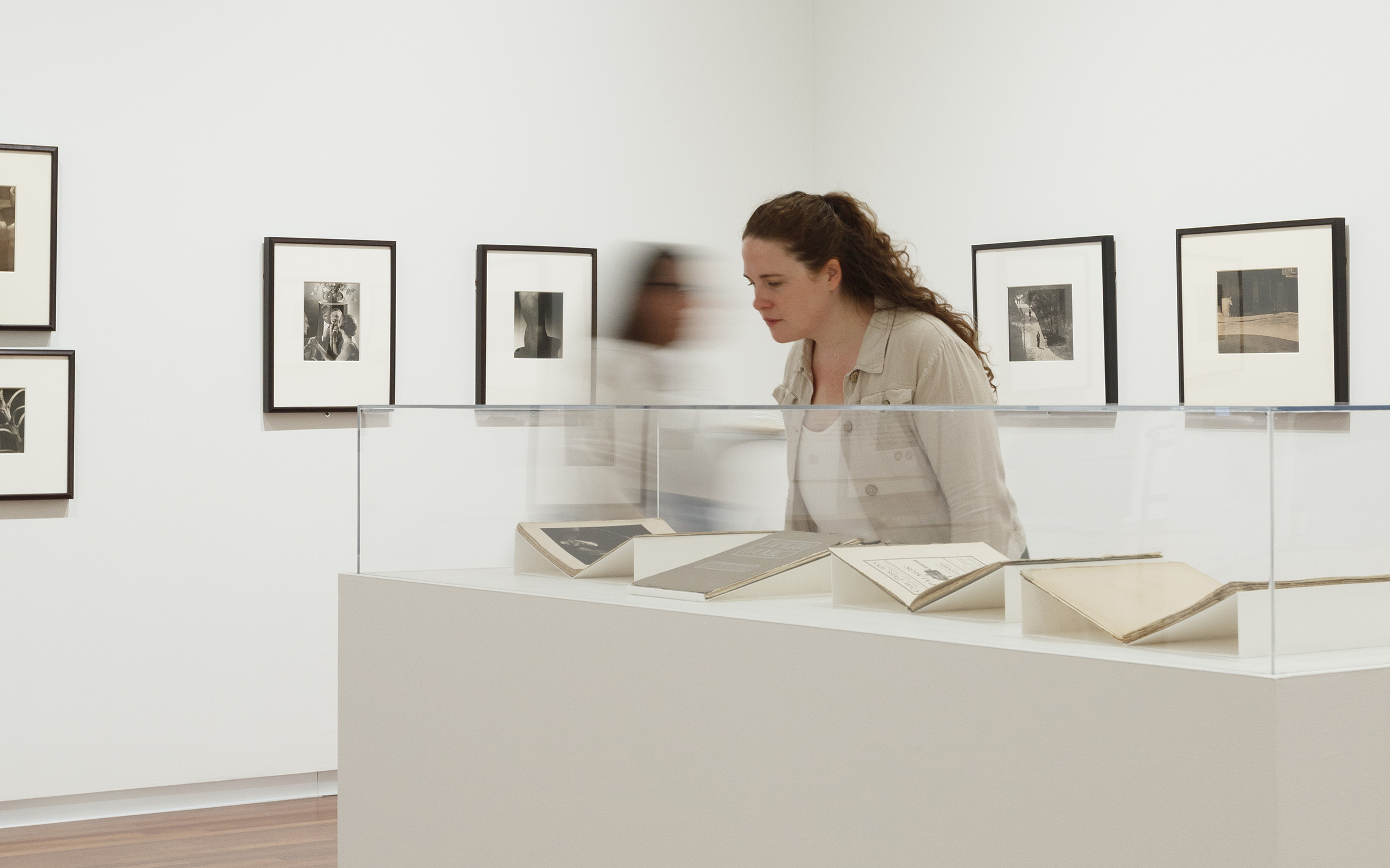 A woman with long, curly hair looks at magazines in a glass display case.