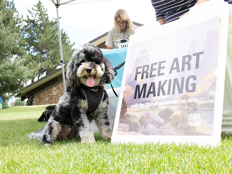 Fuffy dog sits next to sign that says "Free art making"