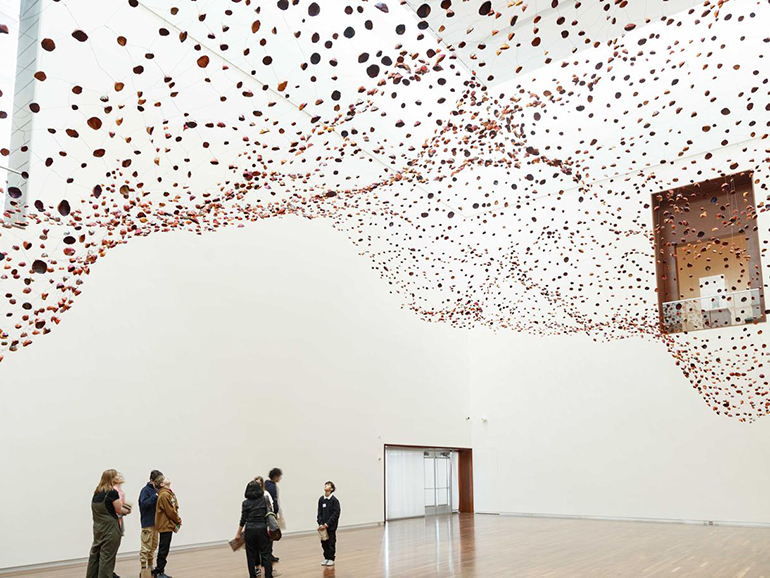 A group of people looking up at the Stone on Boundary installation in the Great Hall.