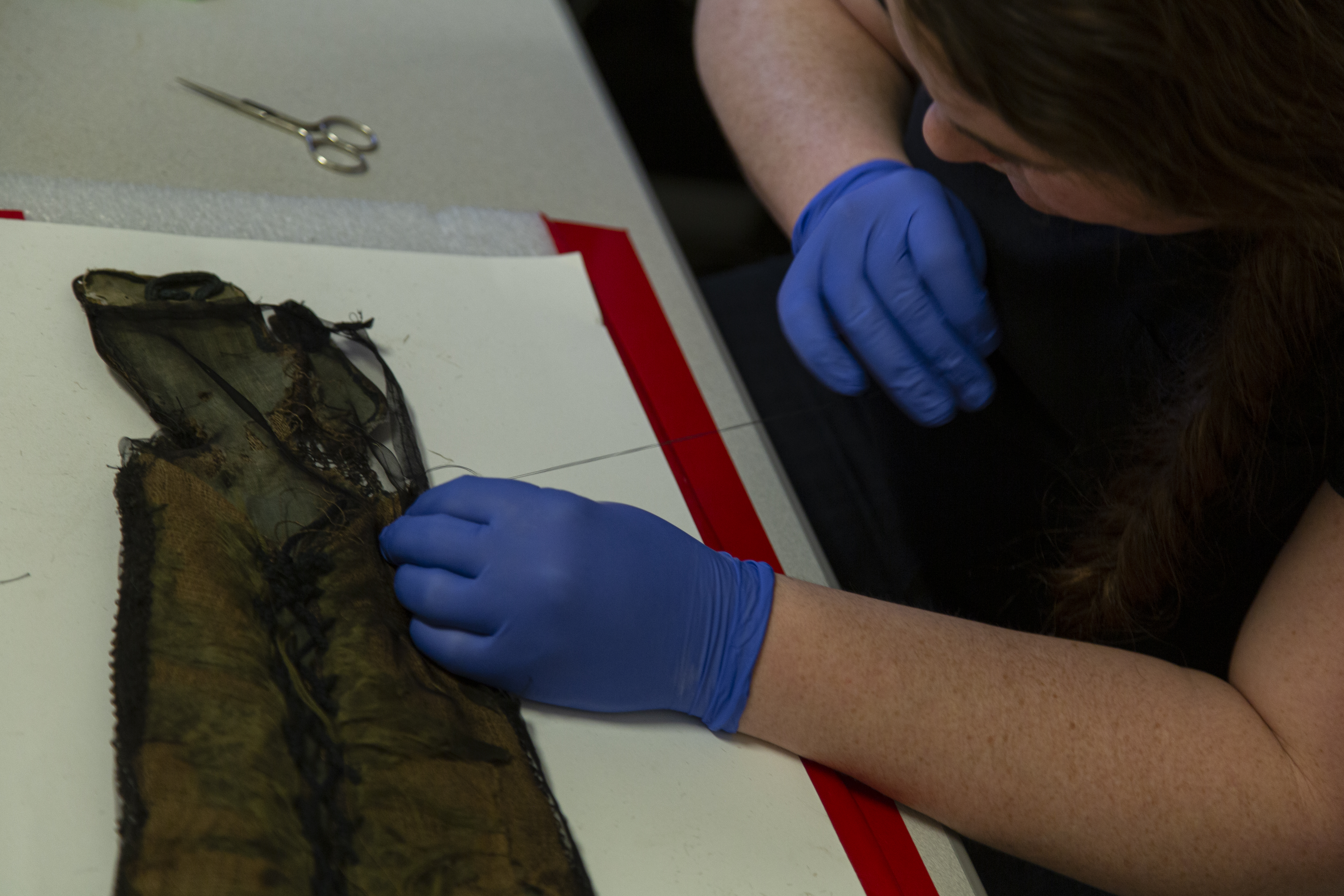 Adelaide Ryder, Collection’s staff member, attaches a layer of silk to the underside of the Samurai Armor sleeve to contain the deteriorated silk and paper.