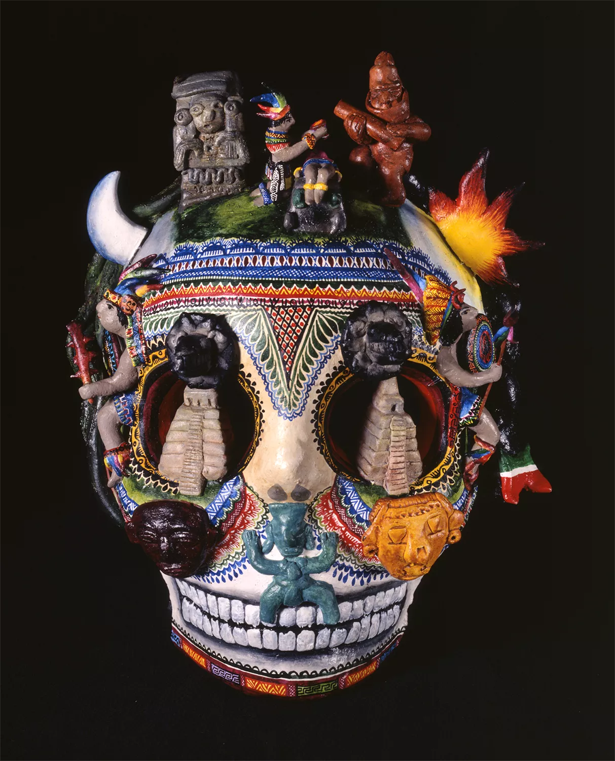 A sculpture of a skull with temples in it's eyes and decked out with colorful imagery.