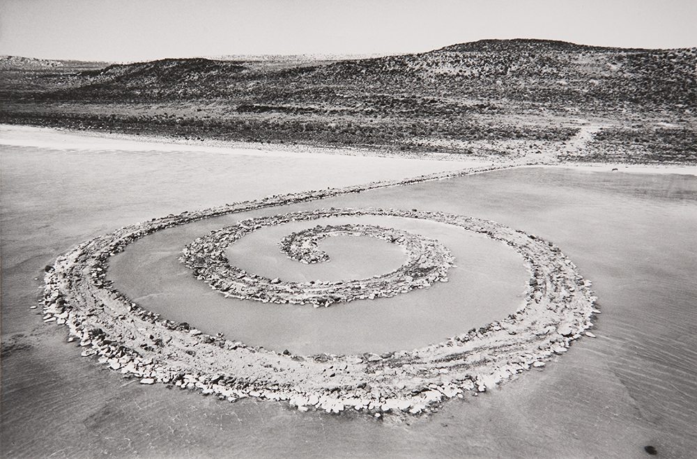 a large spiral in the sand on the beach made of large rocks.