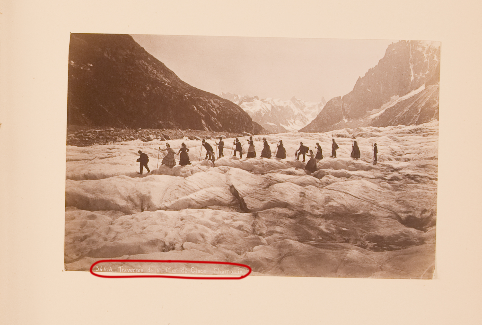 A black and white photograph of a group of people hiking. An inscription at the bottom is digitally circled in red.