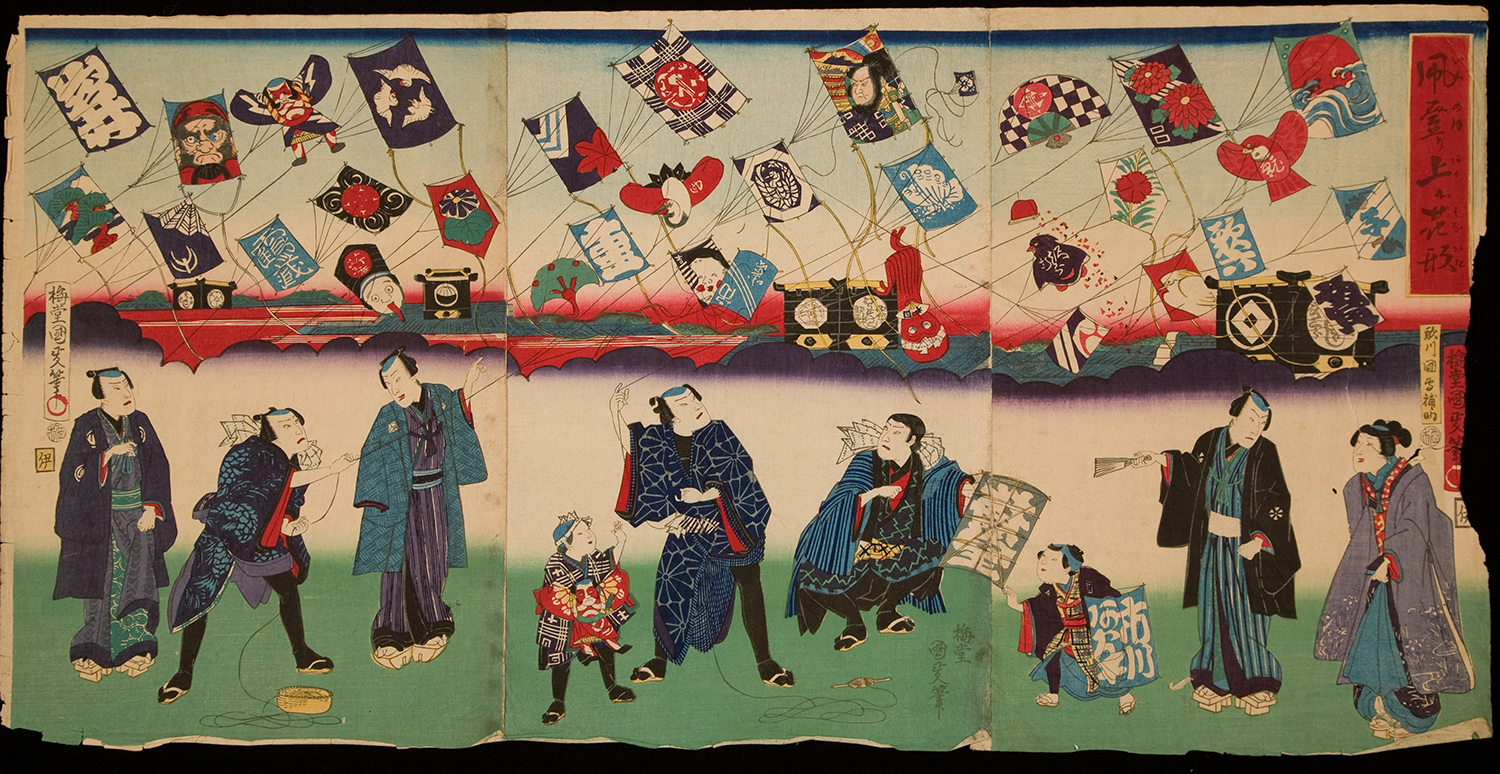 Nine Japanese figures wearing traditional 19th century clothes are standing along the bottom of the print on green grass. They are flying kites above their heads. Approximately 35 kites of different shapes and designs hover over a background landscape of mountains and clouds at sunset. Many of the colorful kites have images or writing on them.