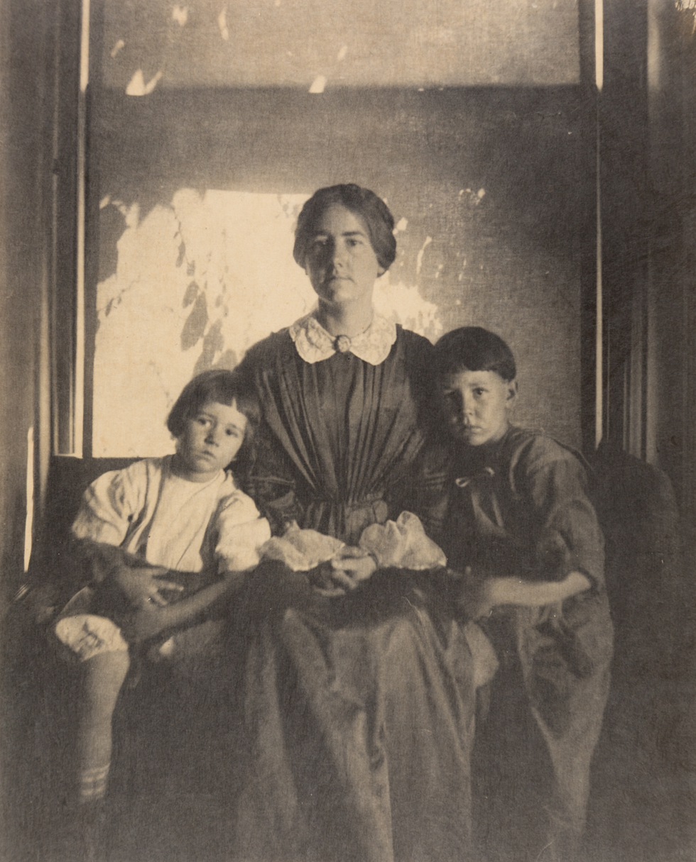 A black and white photograph of a woman sitting with two children.