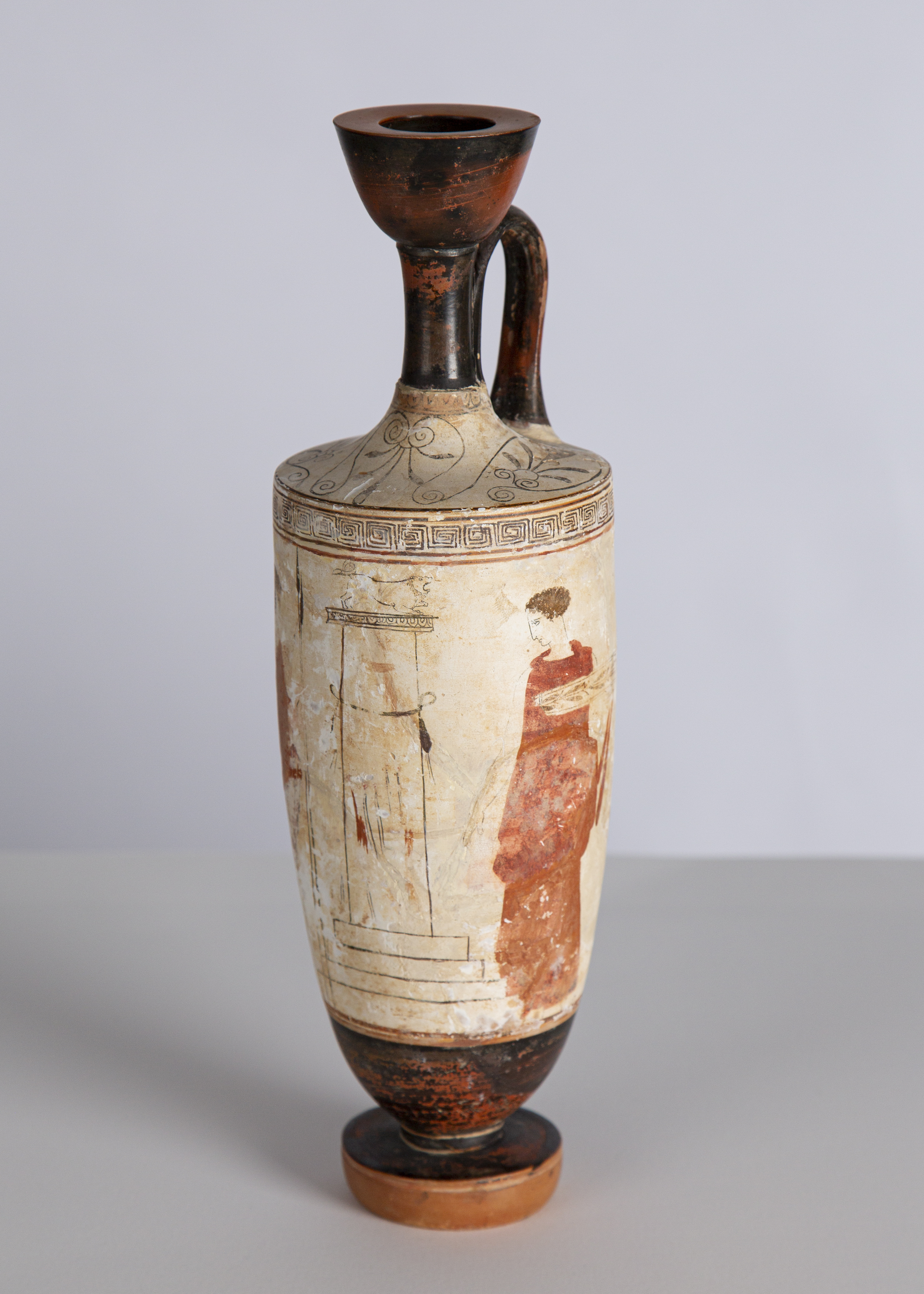 A white vessel with red figures painted on it.