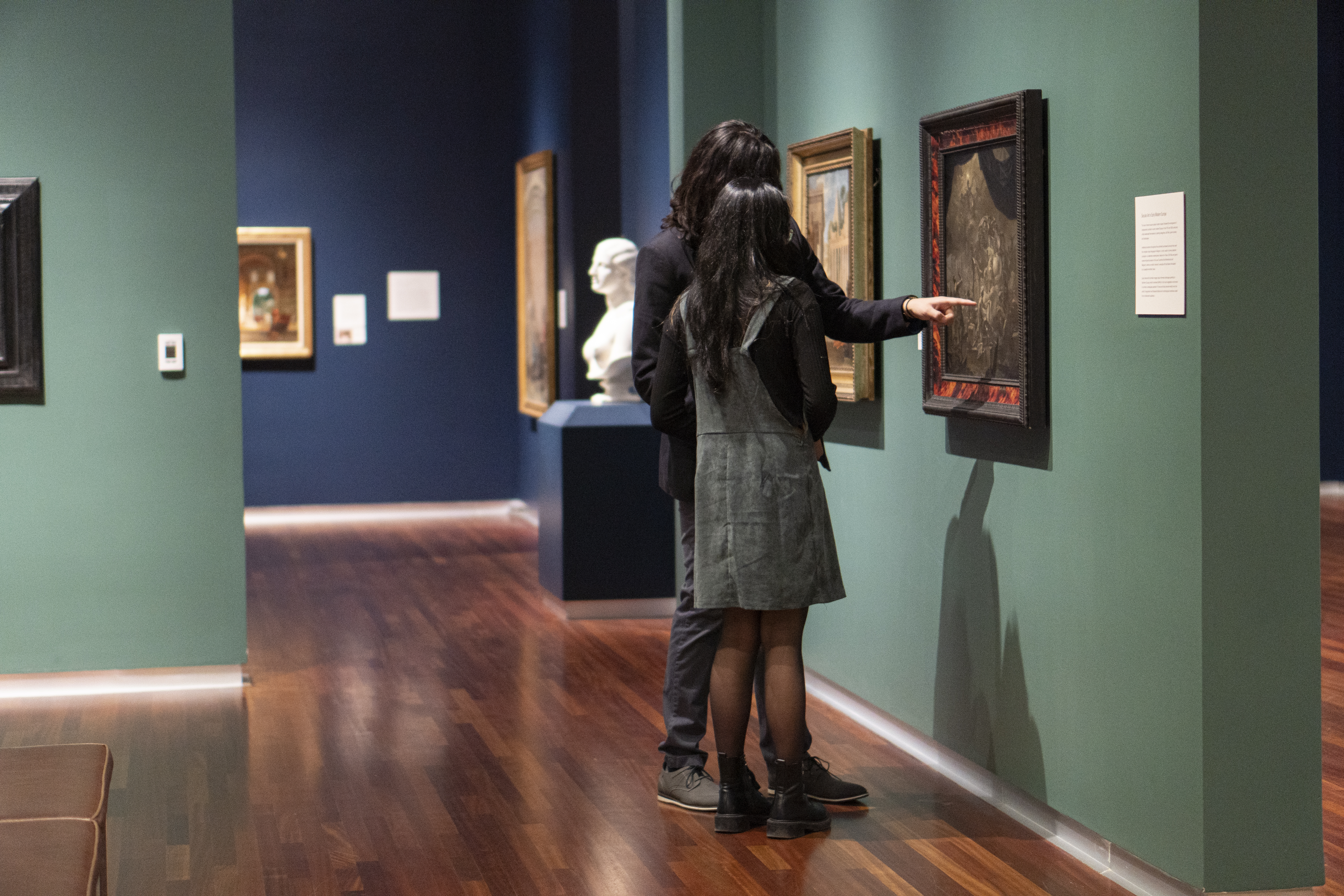 Two women look at a painting in the UMFA European gallery