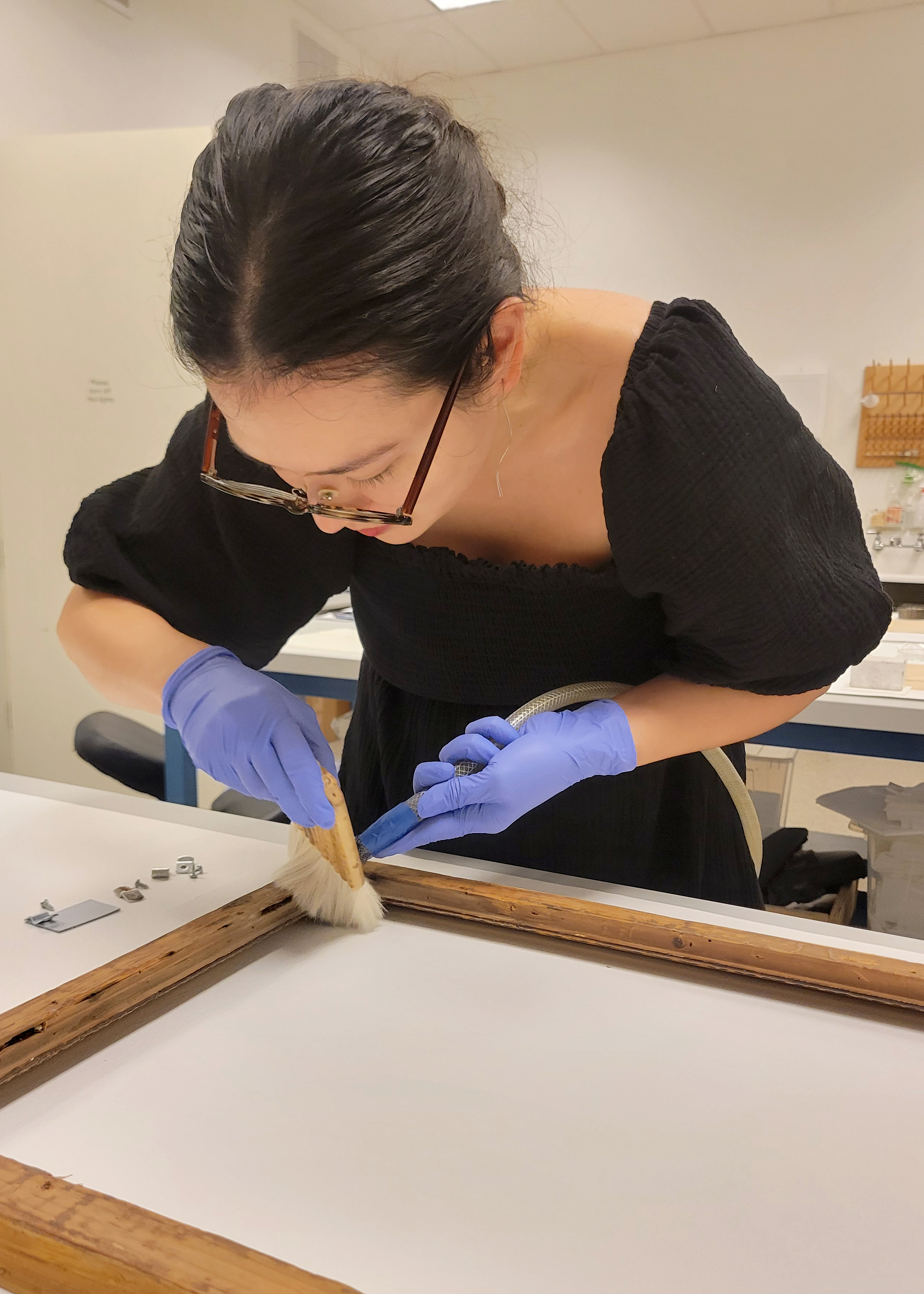 Director of collections, Stacey Kelly carefully brushes a wooden frame.