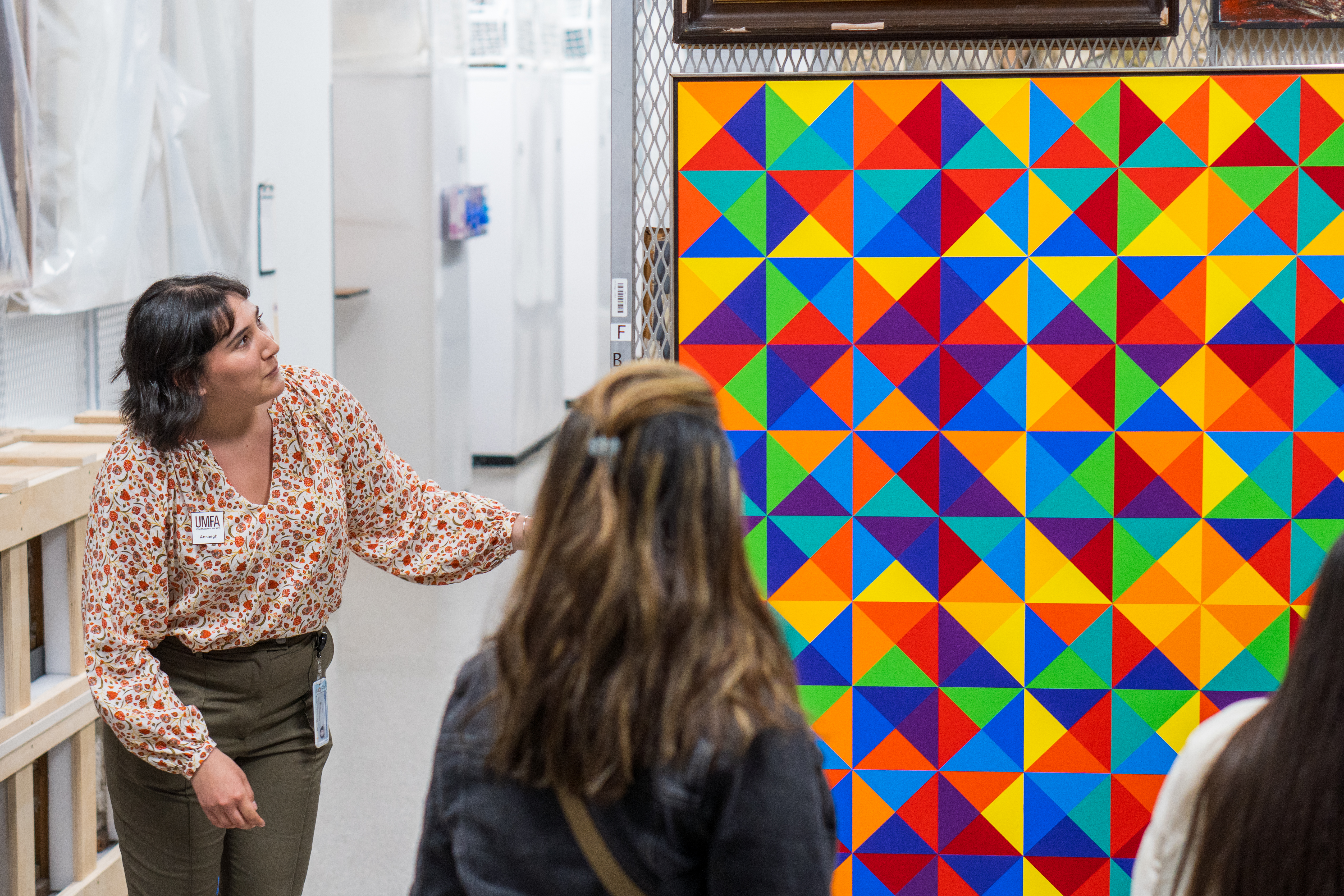 A person stands next to a colorful painting in storage.