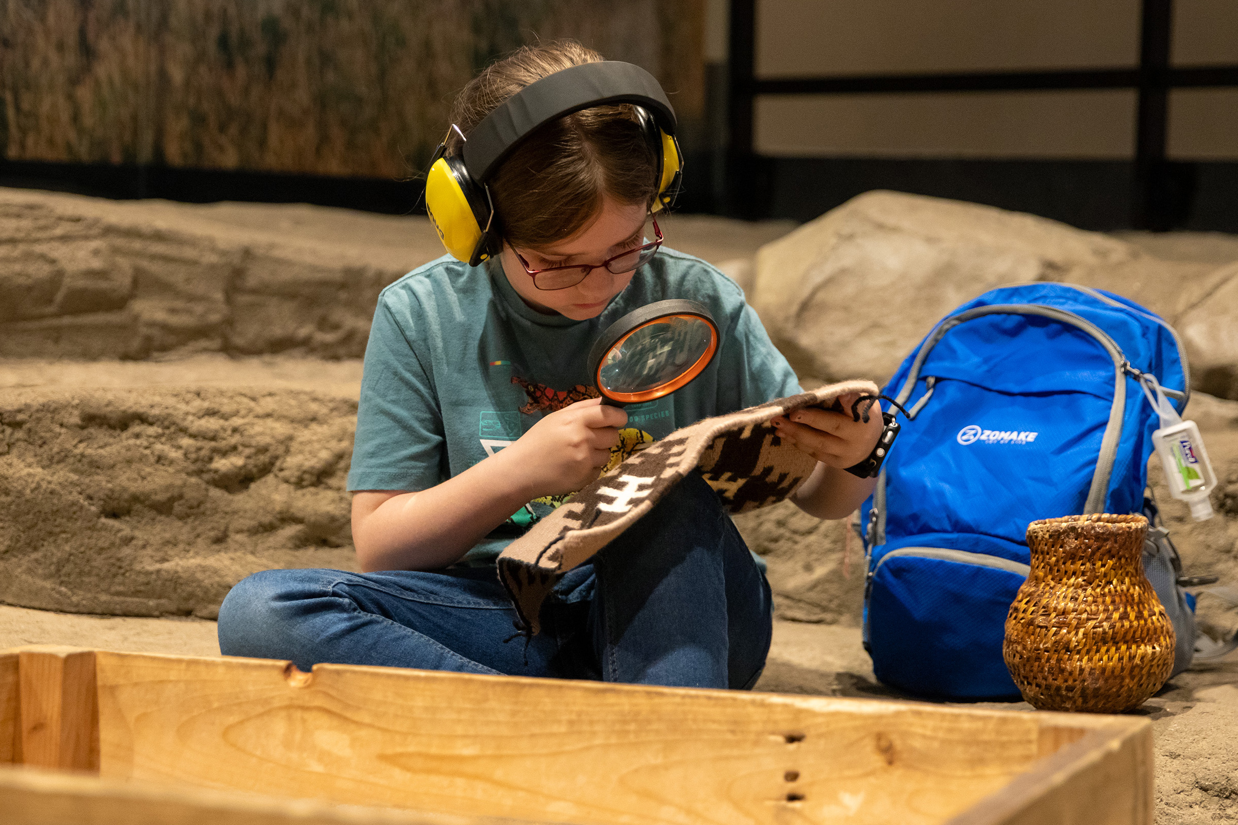 A child wears headphones from a sensory backpack at the NHMU.