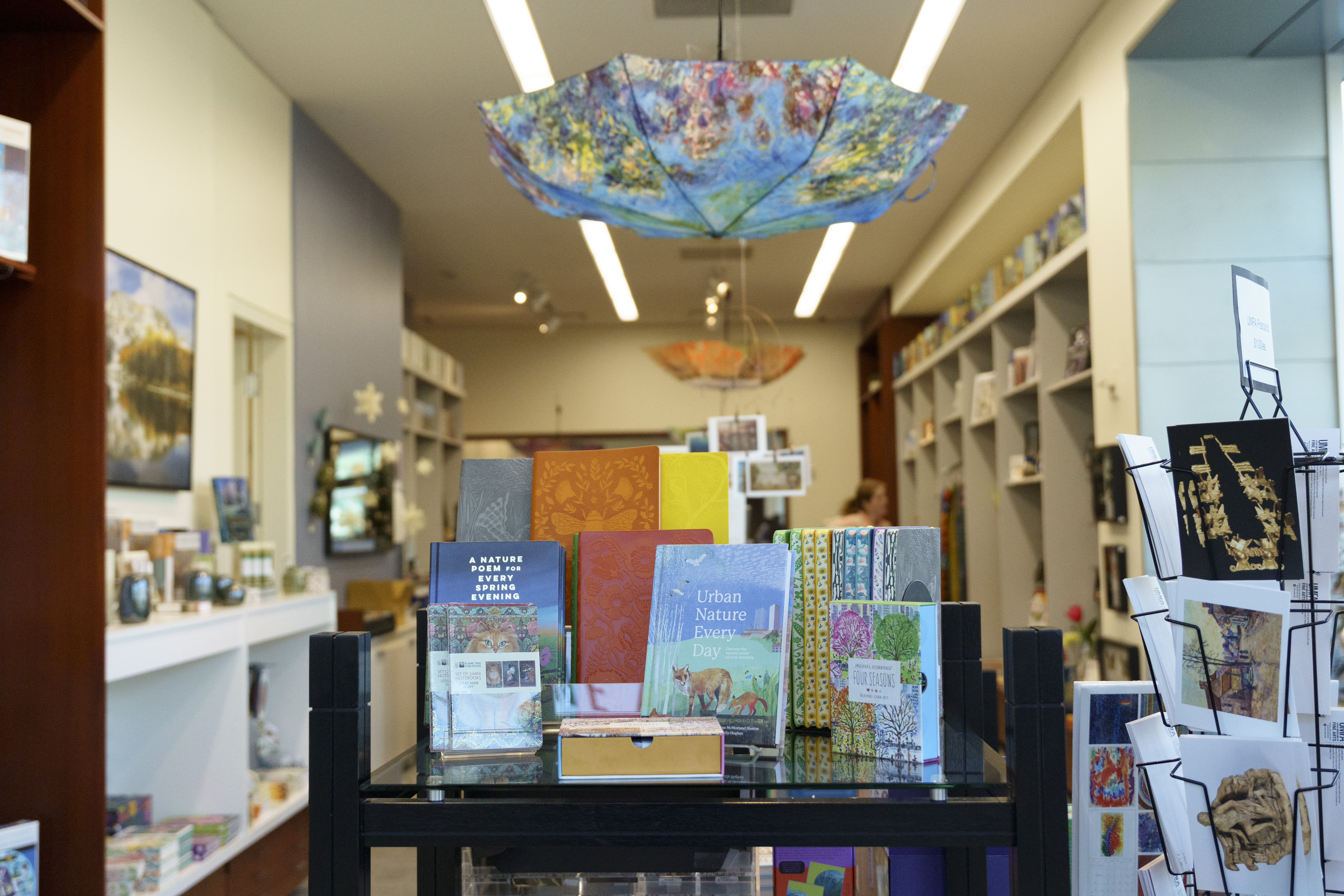 An upside down, open umbrella hangs from the ceiling above a table displayed with different books.