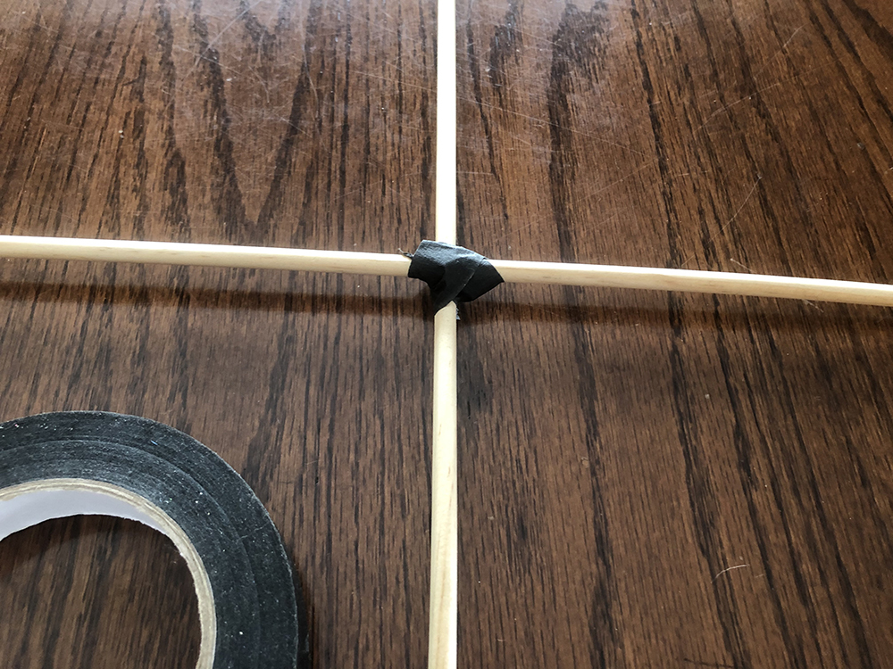Close up of tape covering the strings at the intersection of the dowels