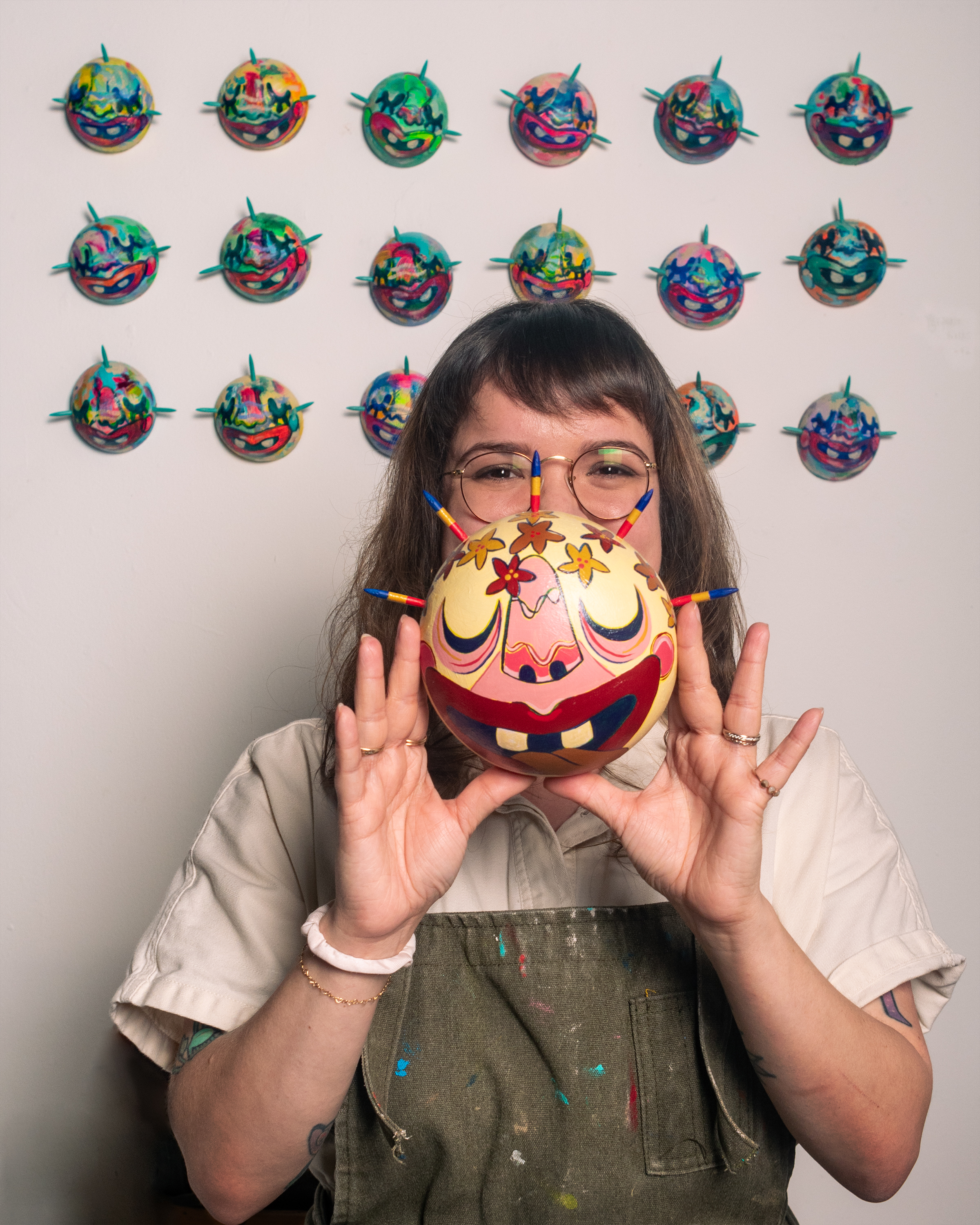 A photo of Allison Martínez Arocho. She is a woman with brown hair. She holds a mask in front of her face.
