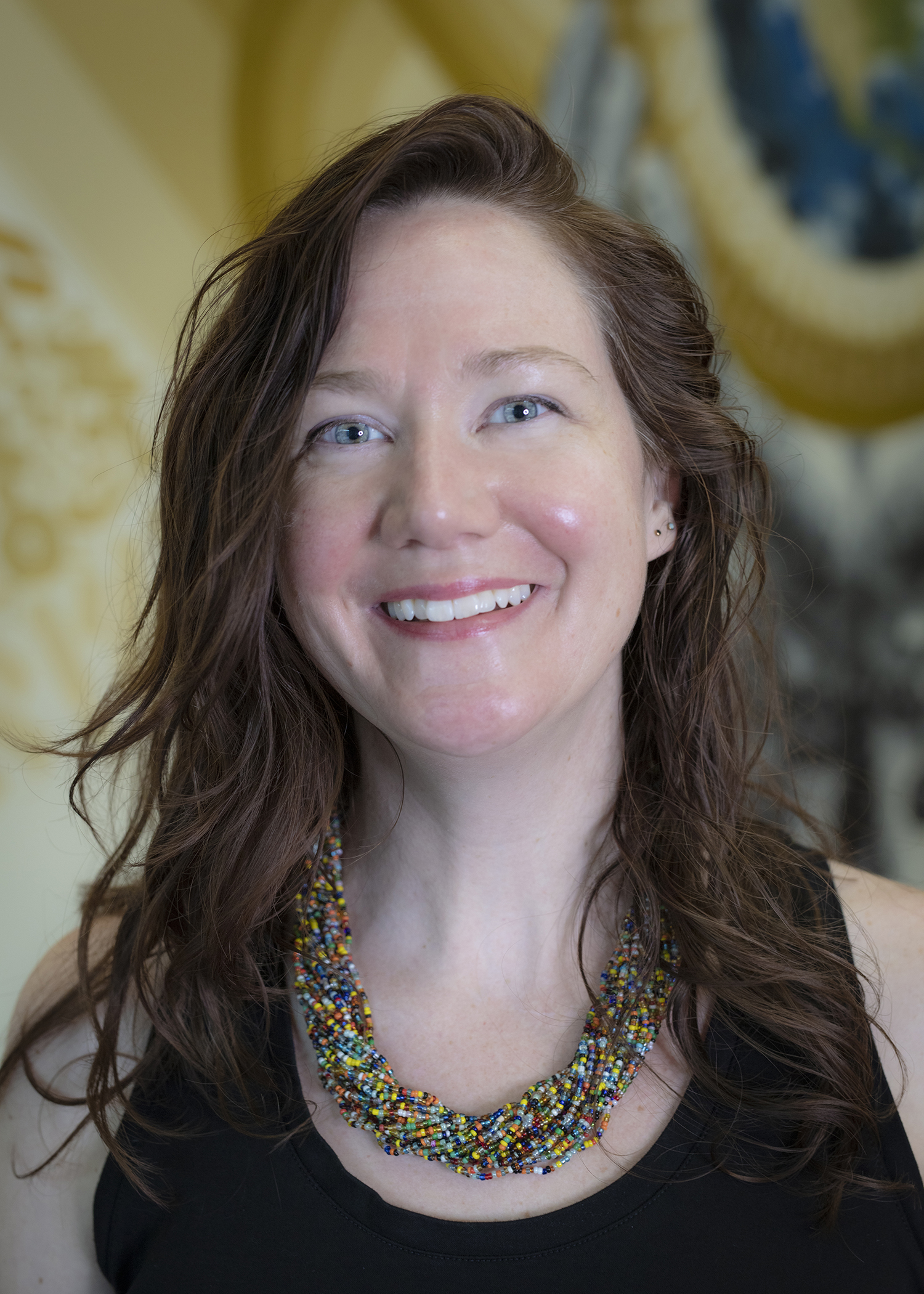 a shoulders up portrait of Alisa Mccusker. She is a bright smile, blue eyes and shoulder length brown hair. 