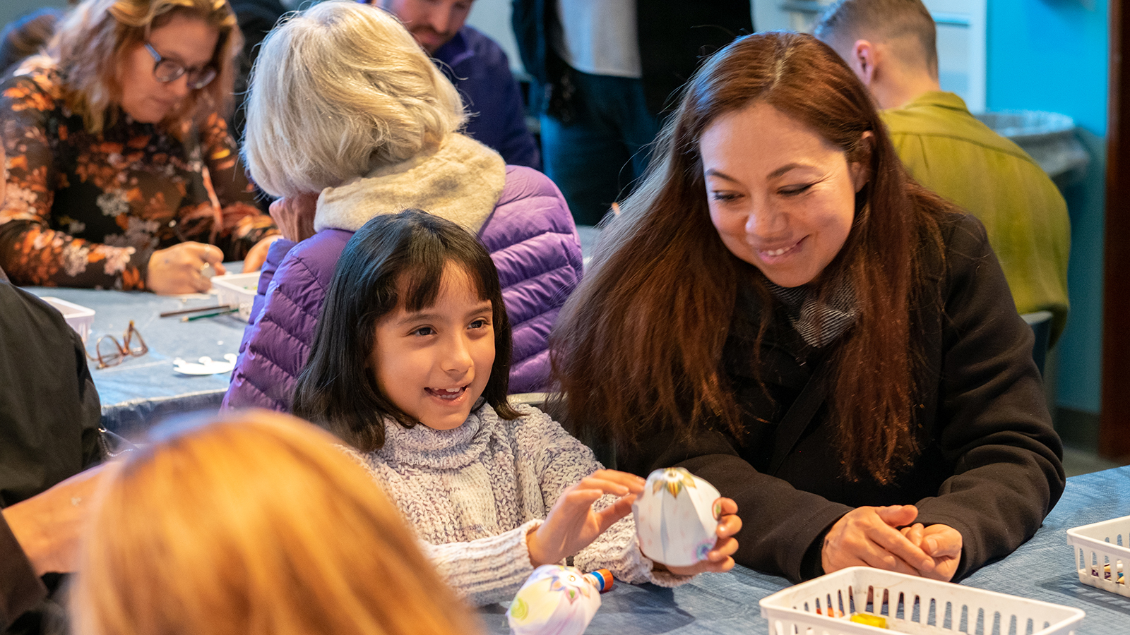 Mother and child sit in UMFA classroom table making paper sugar skulls