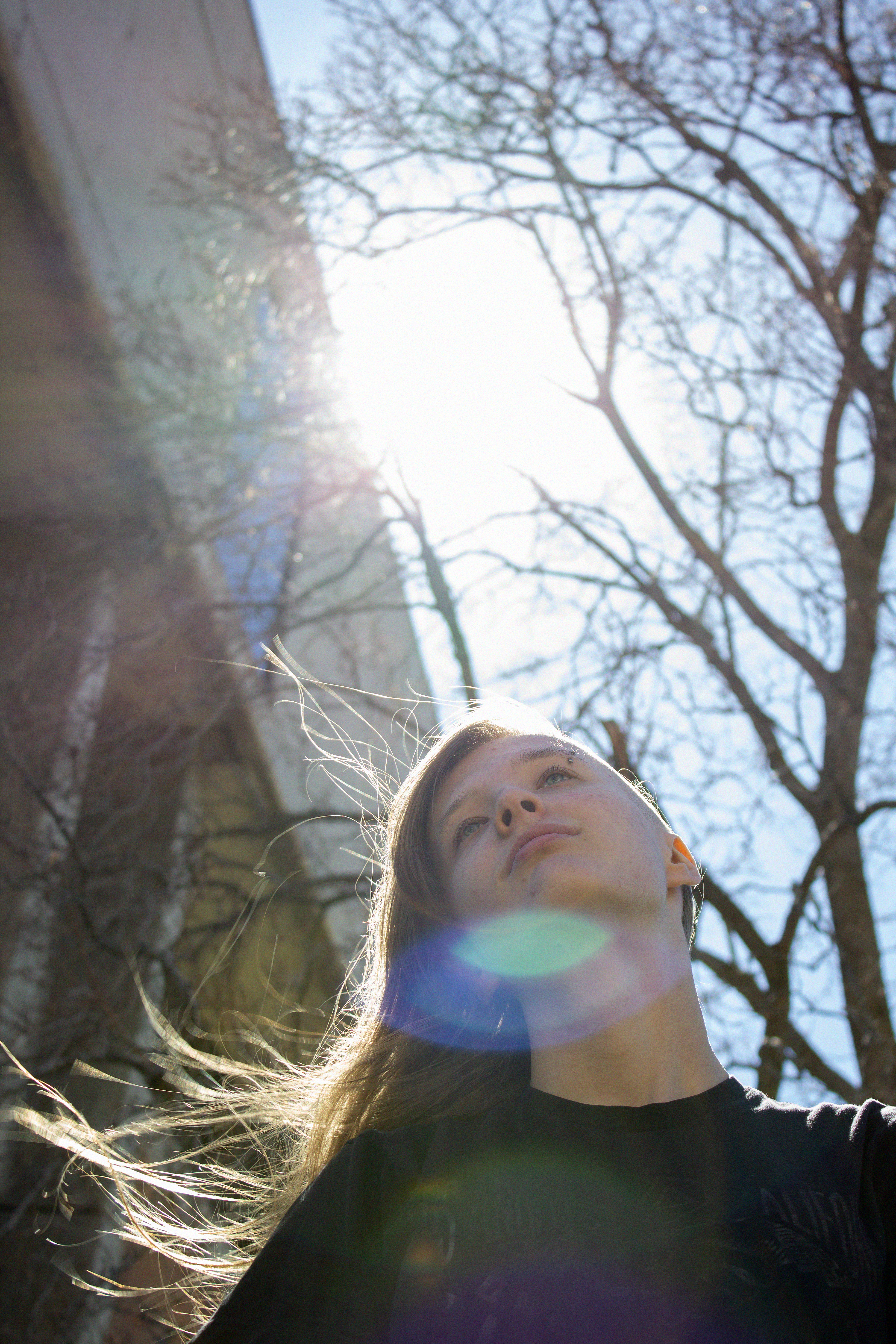 a portrait of a young woman, flipping her long hair in the sunlight outside.