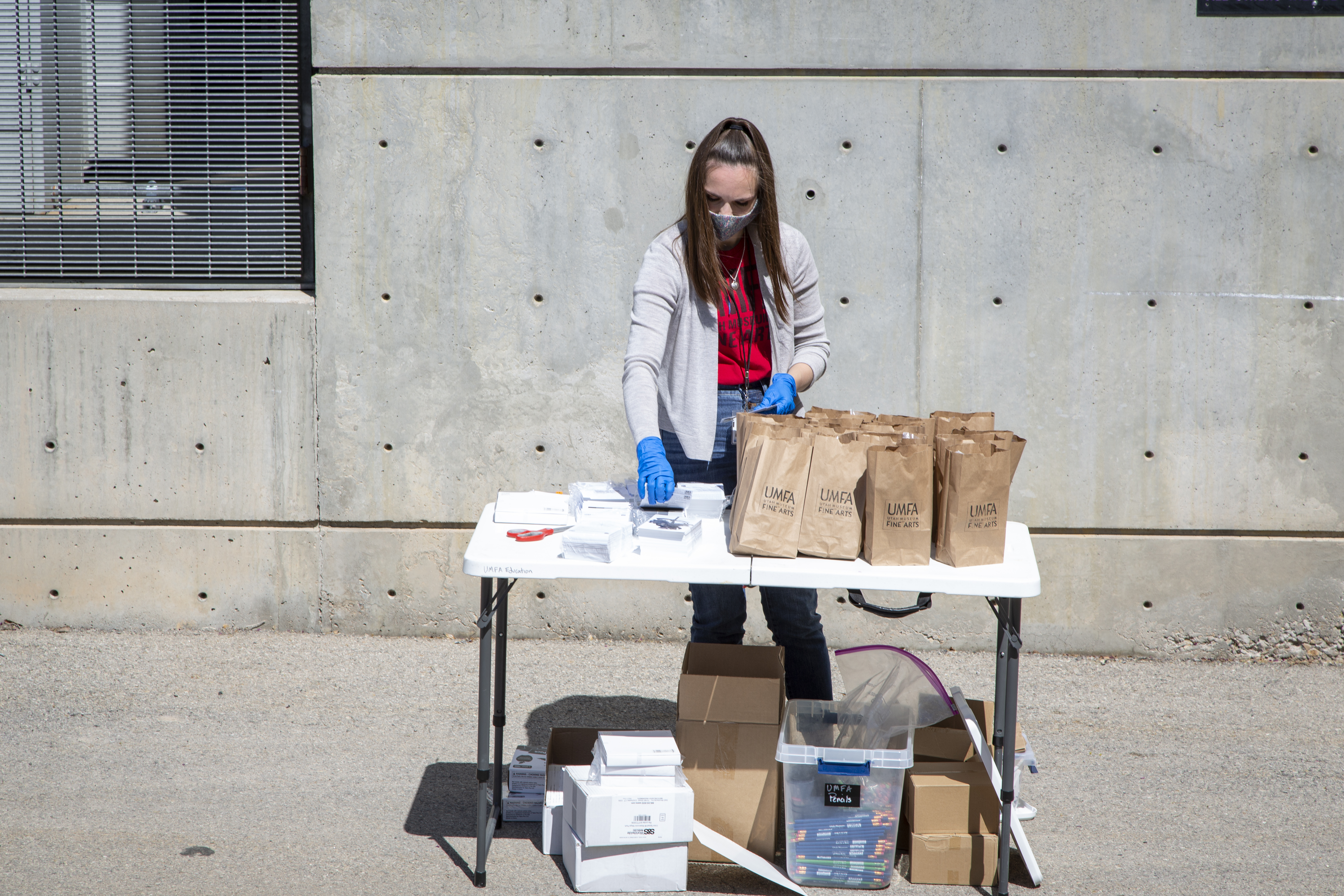 Katie Seastrand assembeling art kits for students  outside in the UMFA parking lot 