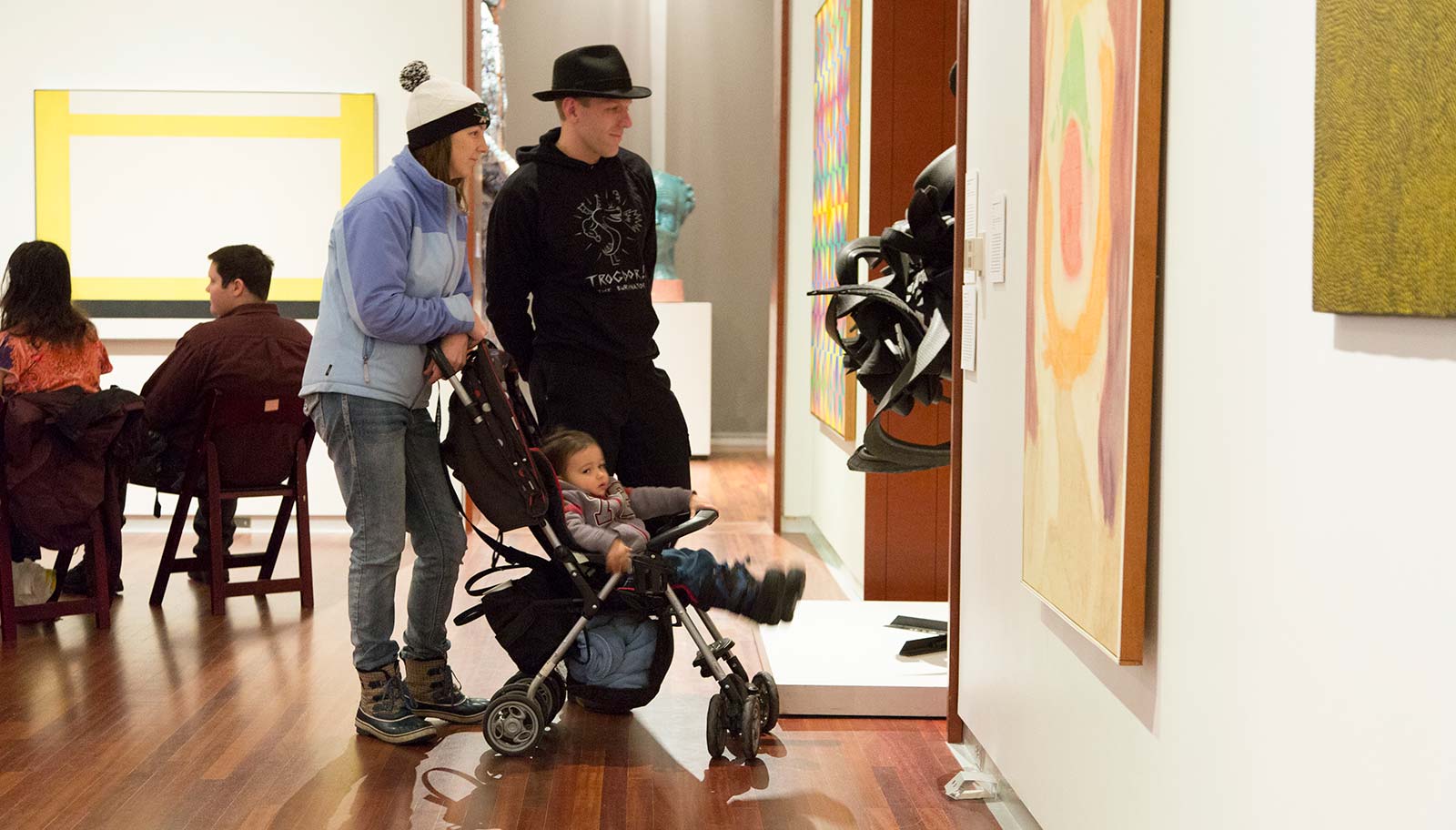 A couple with a child in a stroller view art in the contemporary gallery.