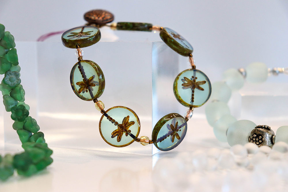 light green glass jewelry on clear acrylic blocks with flowers pressed in the center of each piece of glass 