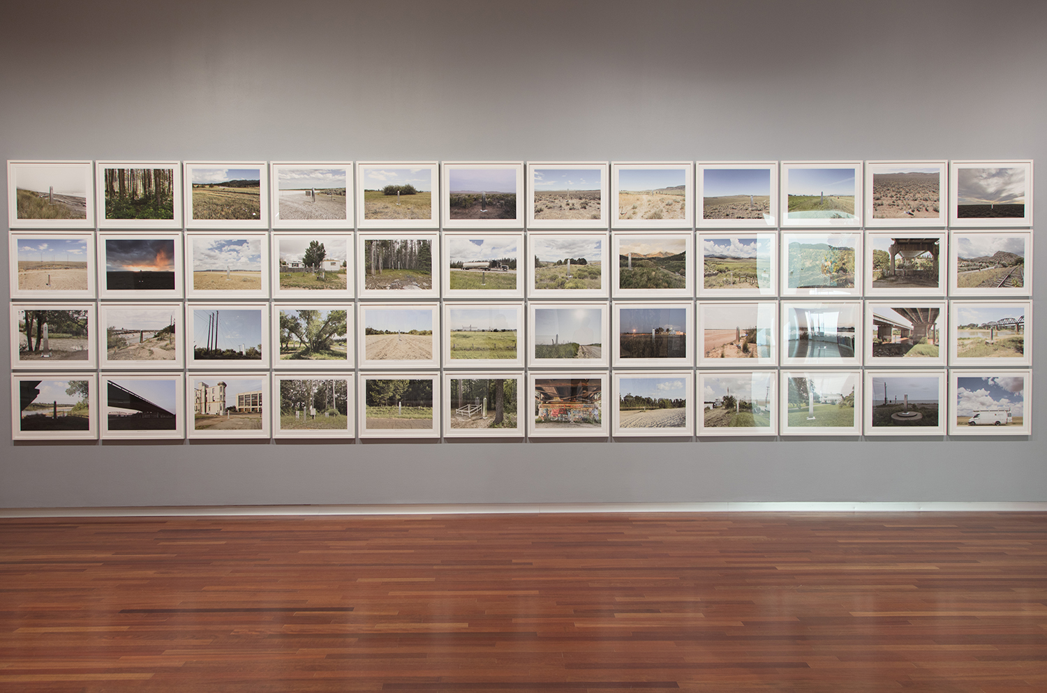 a grid of 48 color photographs of the American west all all depicting different locations with a silver obelisk in them 