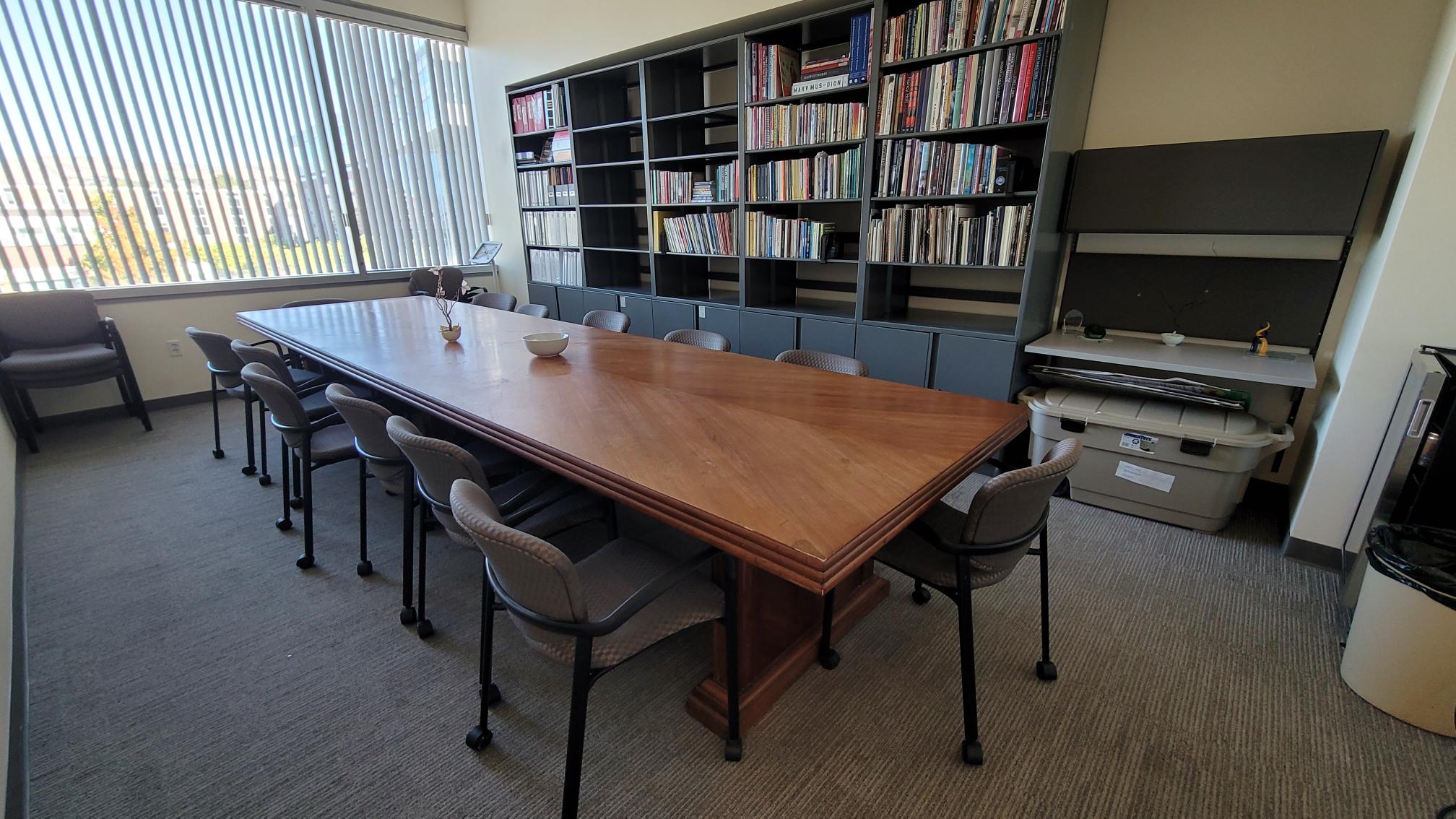 A conference room with a wooden table and a large bookshelf.