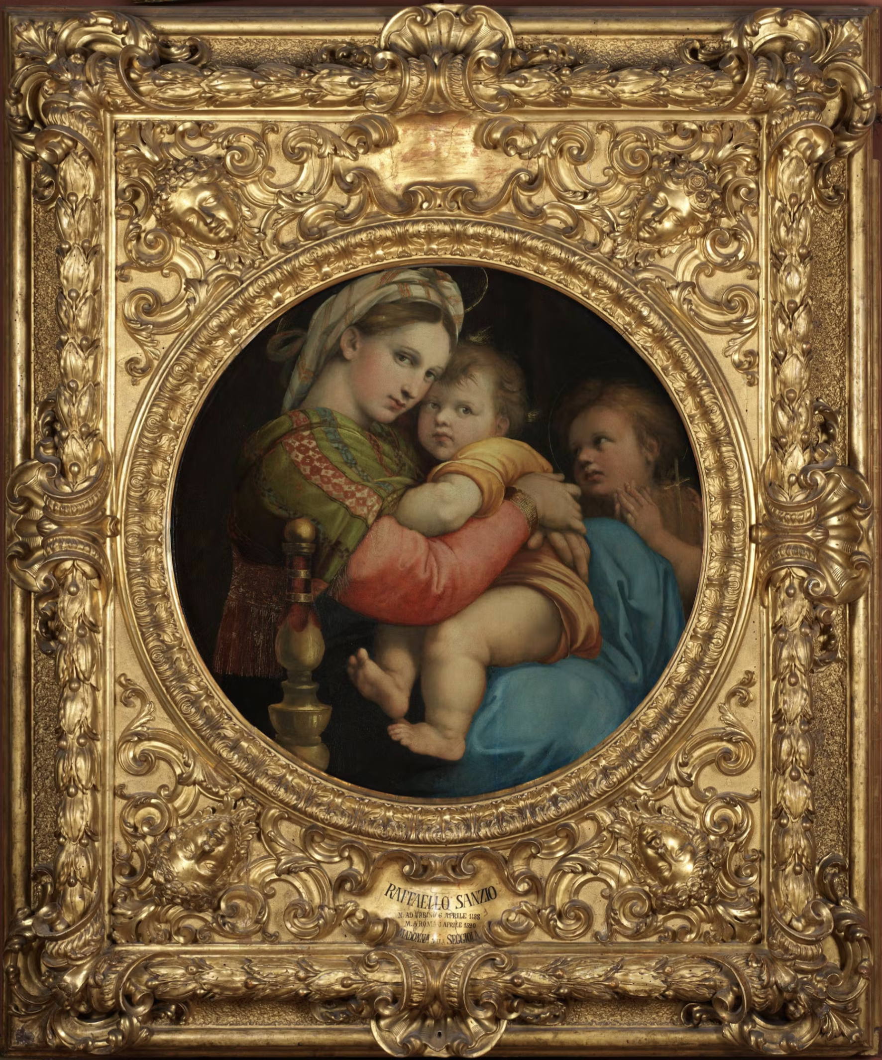 A portrait of a woman holding a child. The portrait is in a gold circular frame.