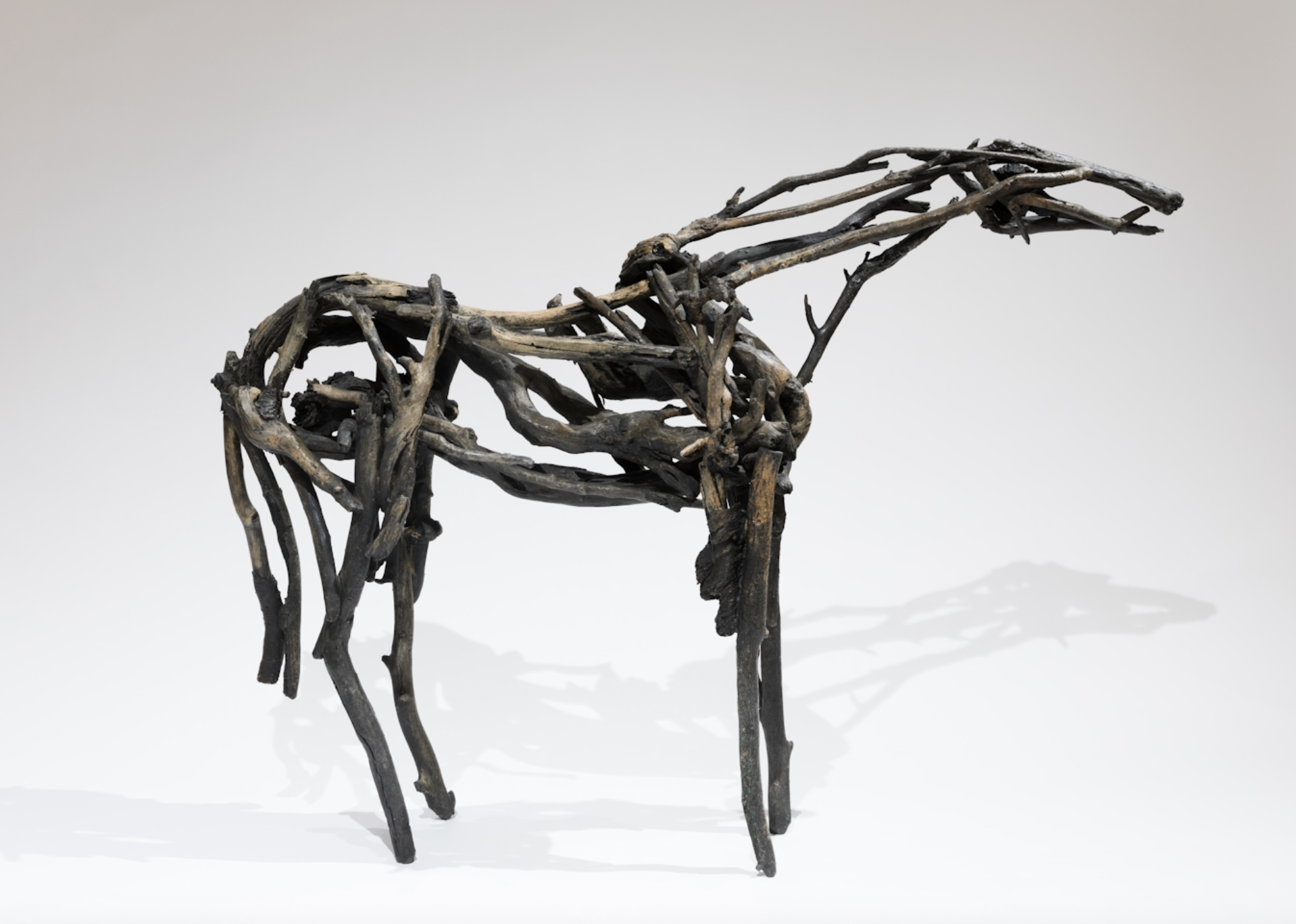A driftwood statue of a horse standing in a white room.