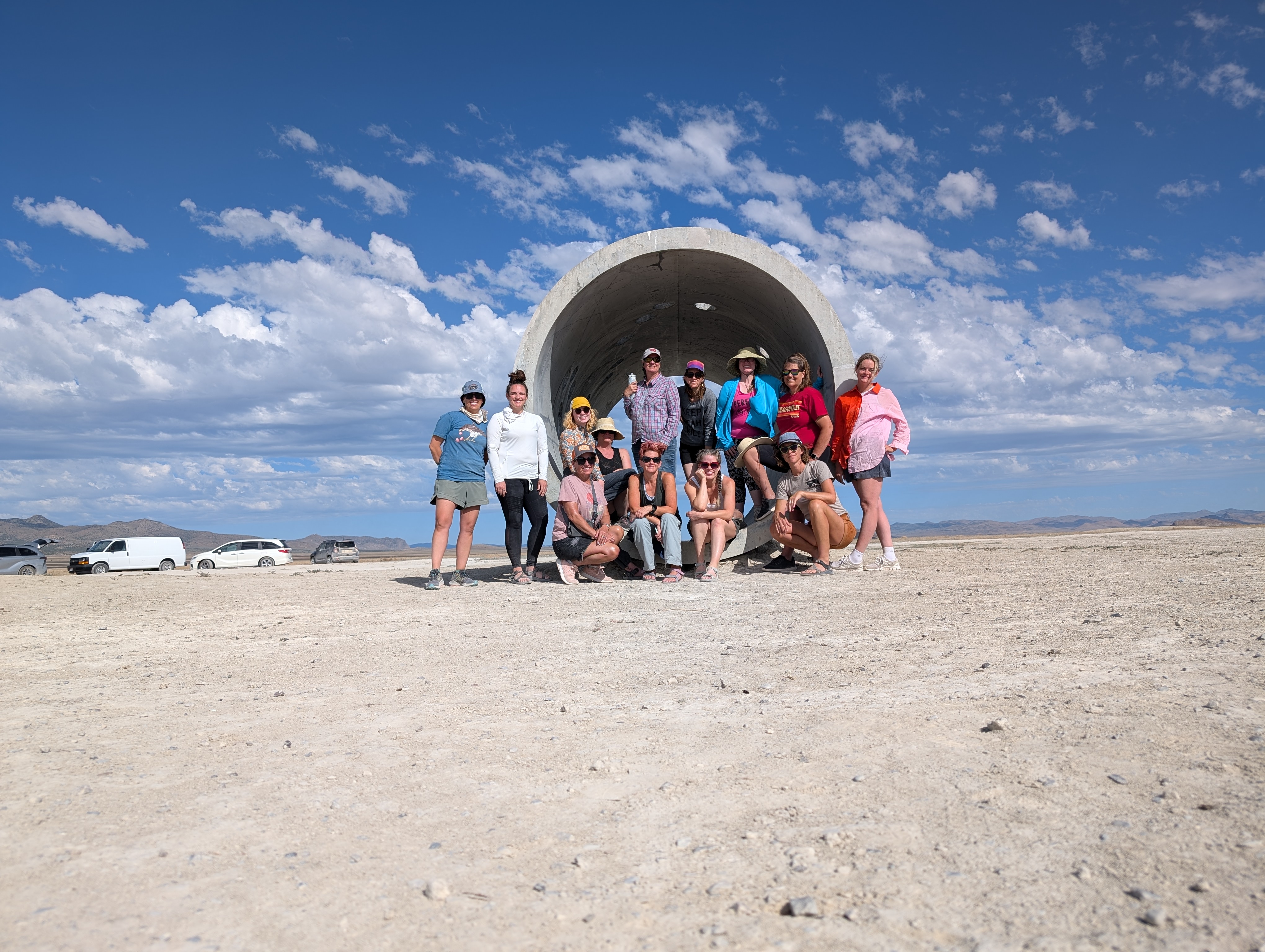 A group of people stand at the mouth of a large concrete tunnel.