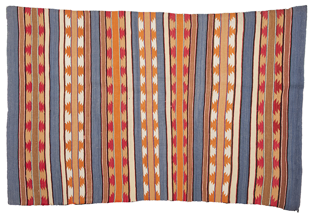 : A woven rug with gray, orange, red, and white stripes. Some stripes have orange or red zigzag triangle shapes repeating throughout the stripe. 