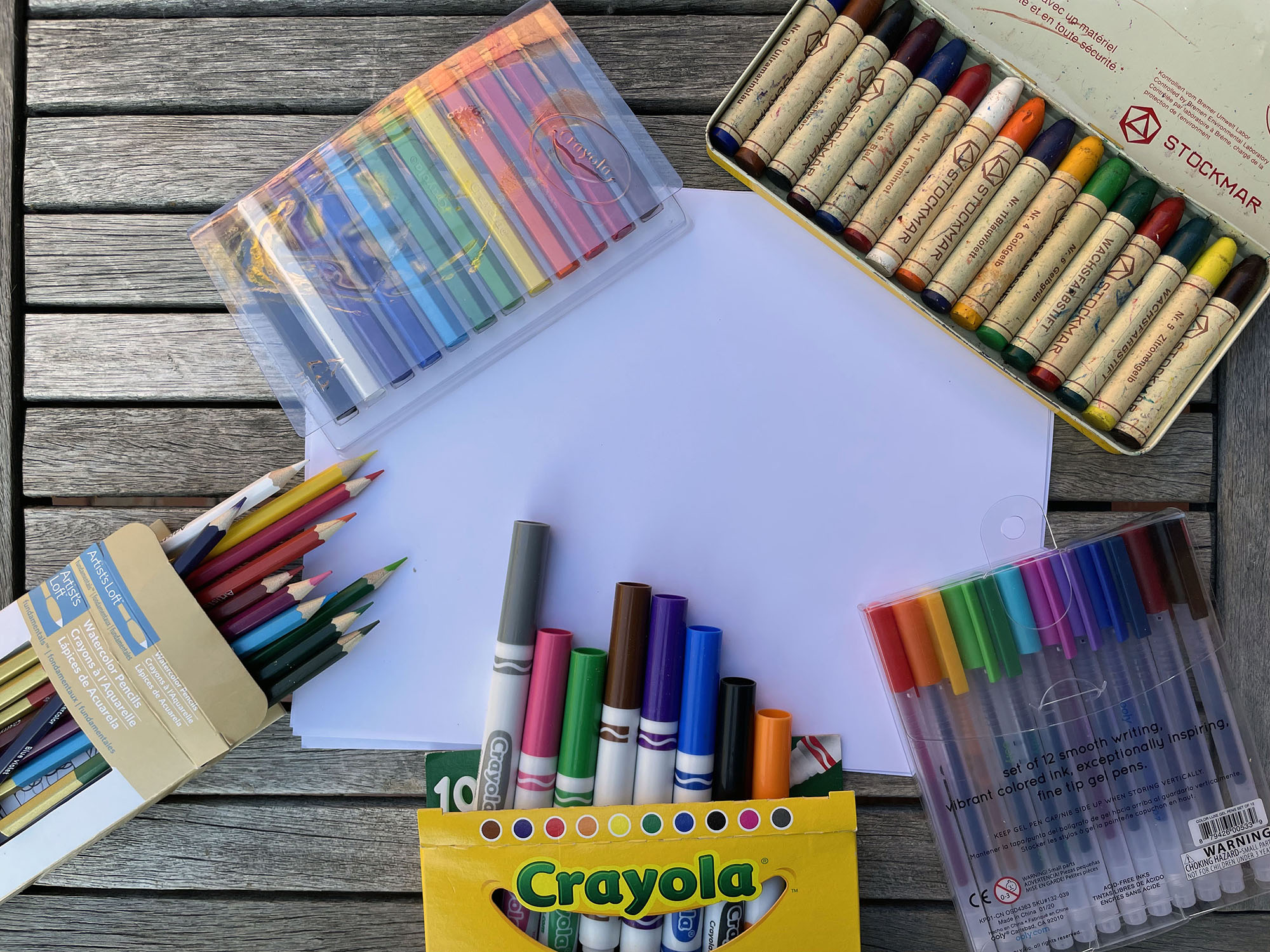 crayons, markers, pens and paper on a wood table