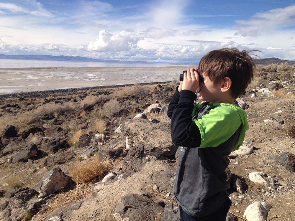 A child looking through binoculars on the shore of the great salt lake