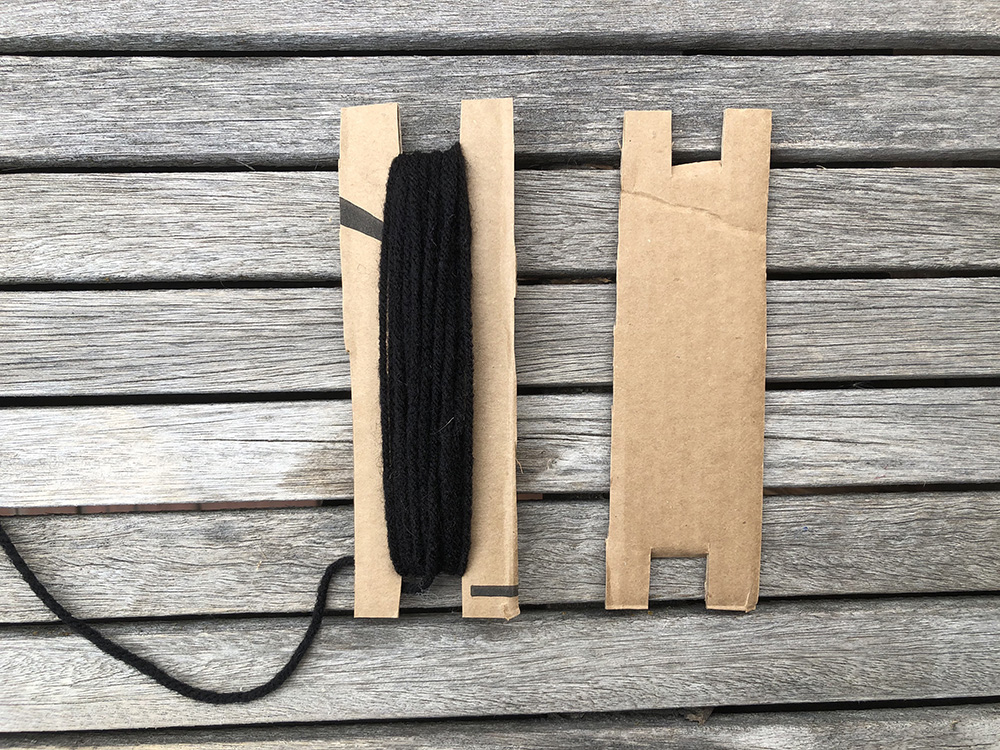 cardboard shuttle wrapped in black yarn