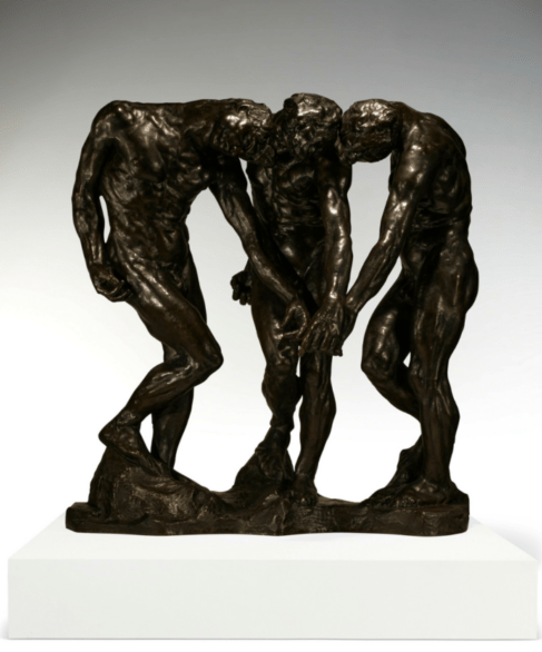 A bronze statue of three figures standing face to face with their hands extended towards the ground between them.