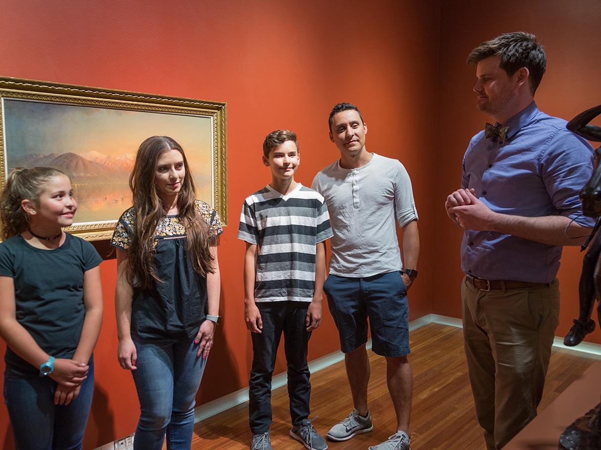 A teacher and a group of students have a discussion in the gallery.