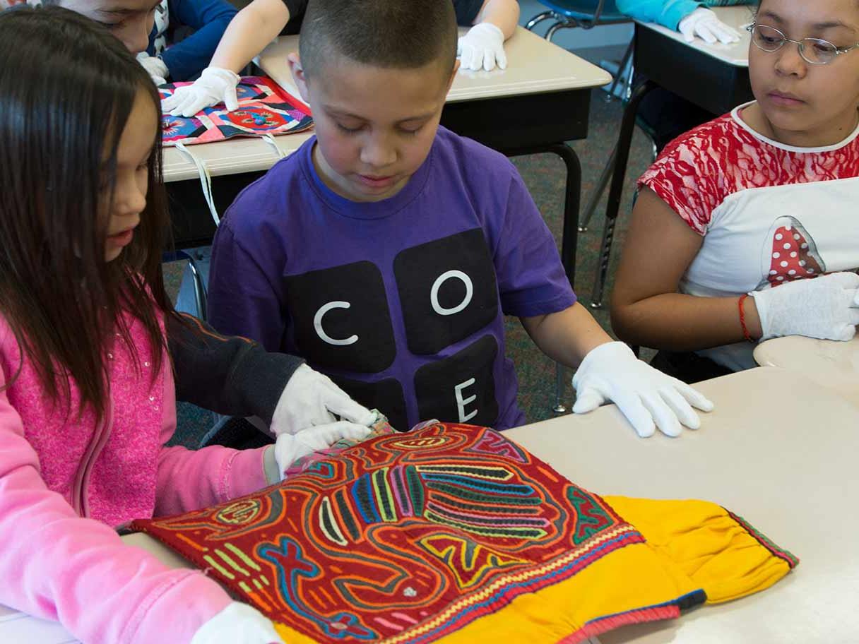Two students examine an embroidered work of art.