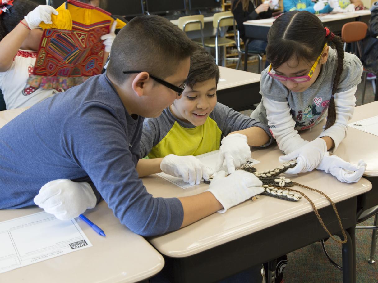 Group of students examine a work of art in a classroom.