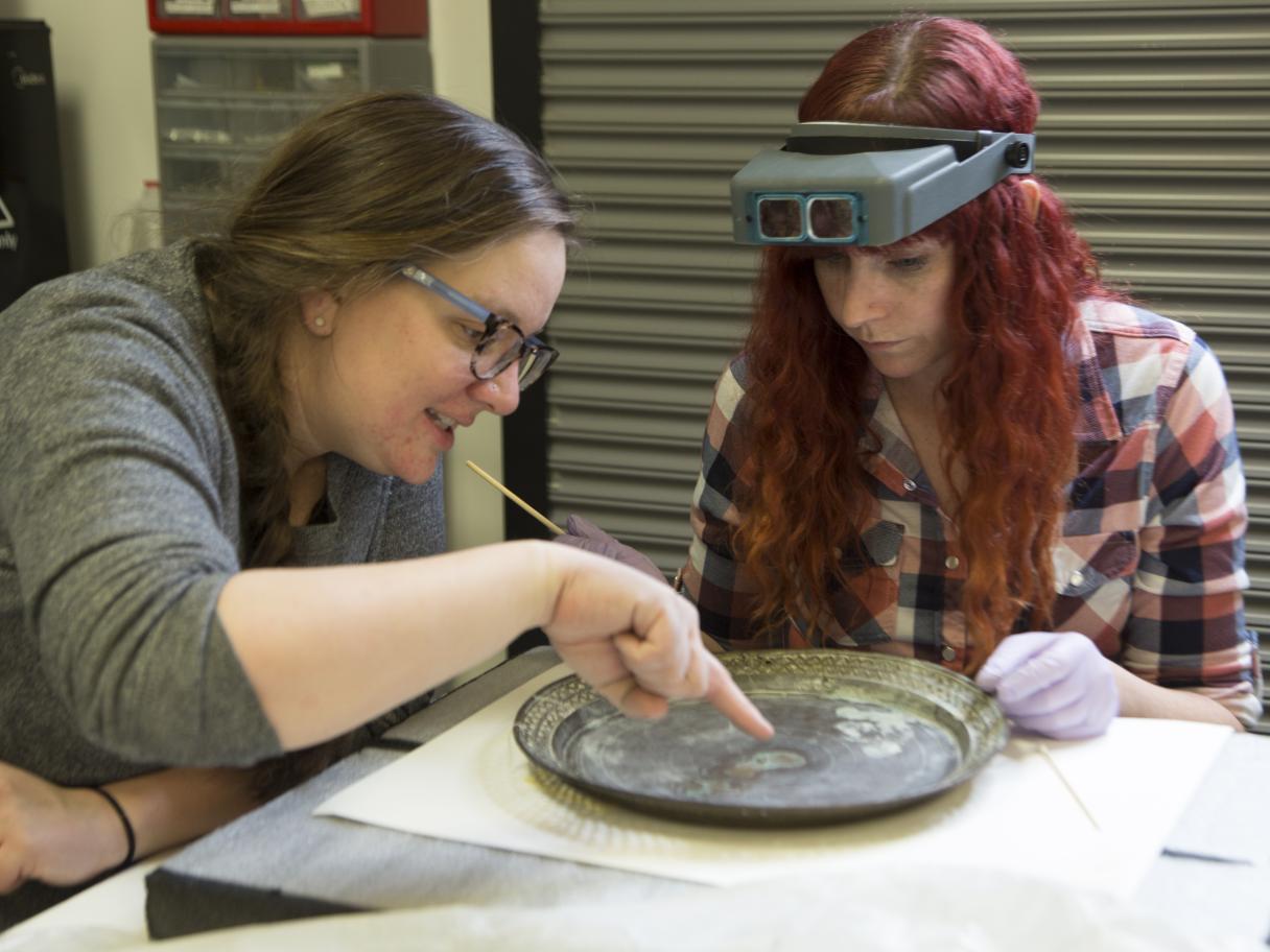 Conservator Robyn Haynie works with IMLS intern Rebekah Abbot to asses a 500-year-old Chinese gong. 