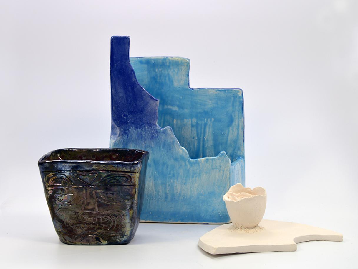 Identity by Zoe Hoopes, Leilani Zamora and Kalayee Hokum Identity by Zoe Hoopes, Leilani Zamora and Kalayee Hokum, three ceramic object, square black vase, blue vessel Idaho and Utah state shapes, white crescent with small white cup attached