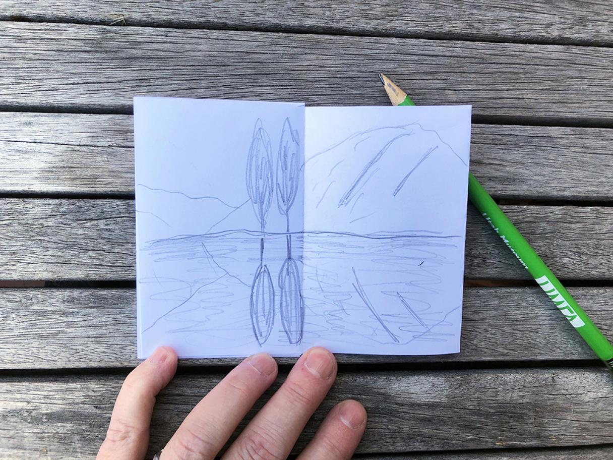 white paper with a drawing of a pond with two trees on the shore reflected in the water