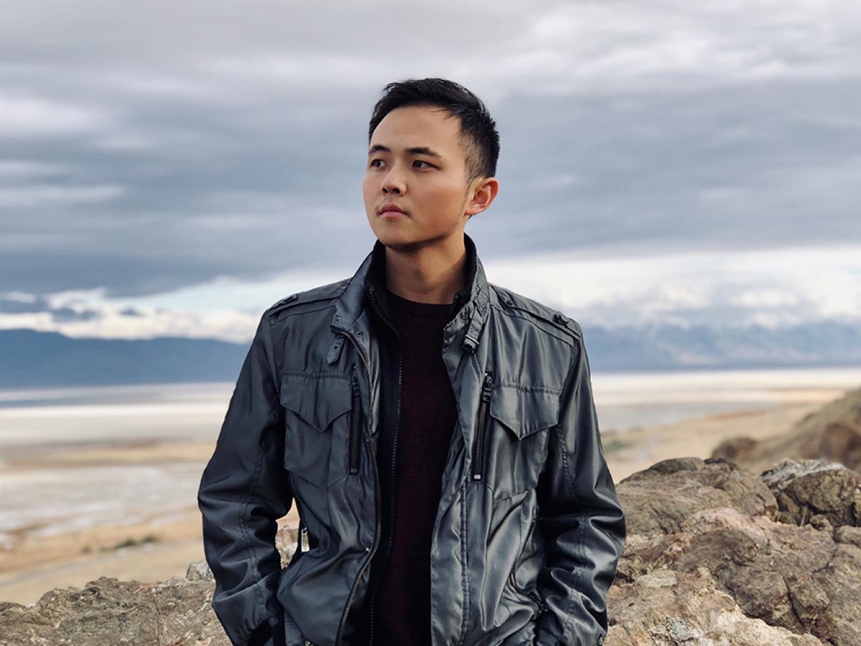 Zheng Zhou in a black leather jacket standing in front of the Great Salt Lake