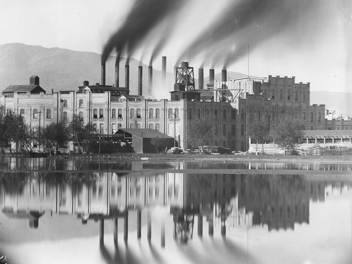 Black and white antique photo on a factory with smoke stacks along a river