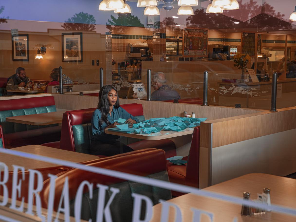 photograph of a women sitting at a table in a diner 