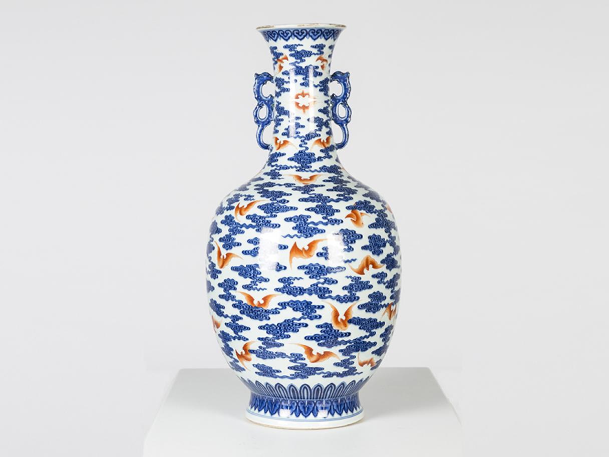 A larger porcelain vase with a pattern of red bats and blue clounds